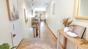 Un couloir comprenant un coin repas, un escalier et une console sur laquelle est posé un panneau.