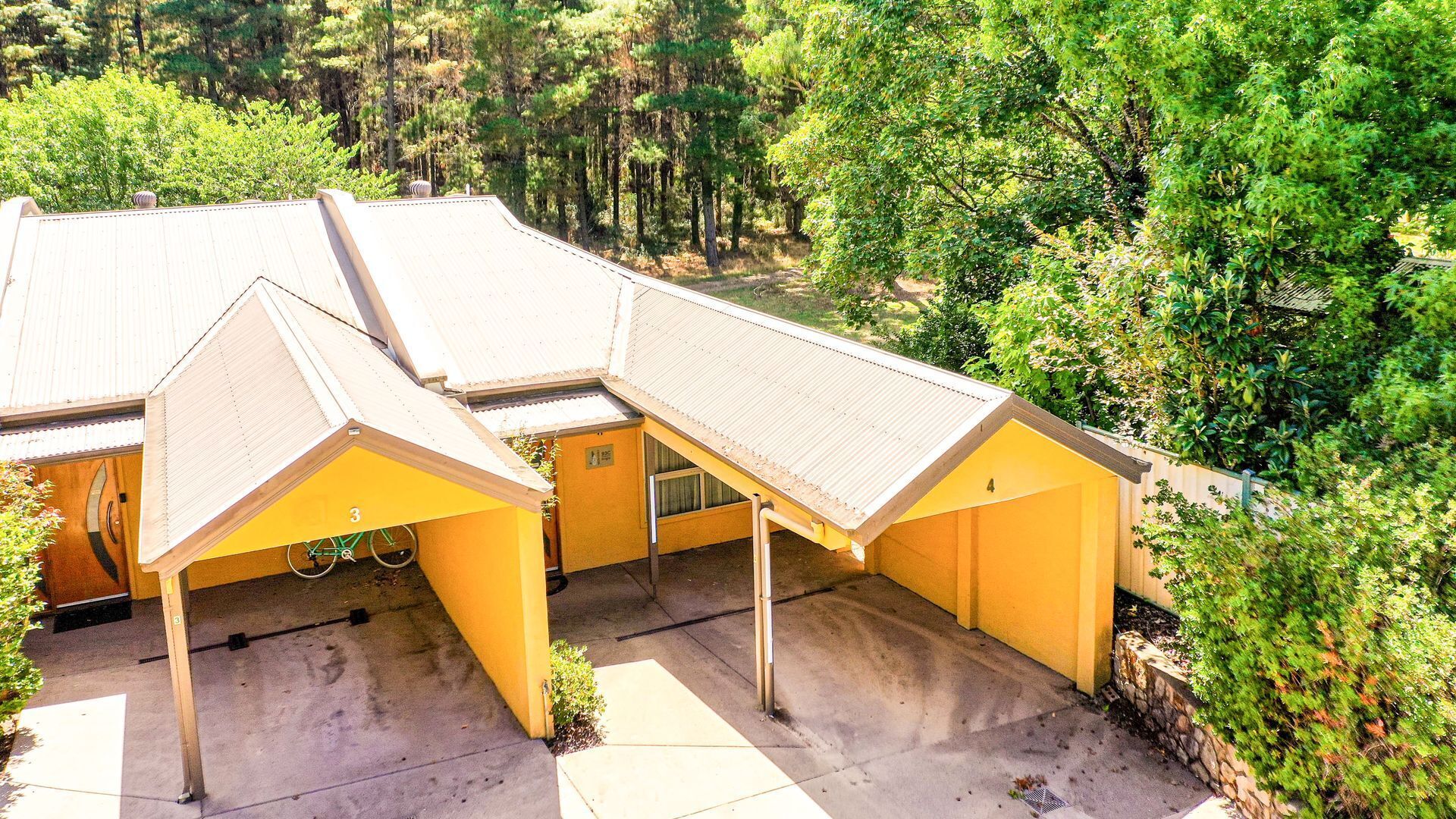 Un edificio amarillo con varias construcciones adosadas, rodeado de un bosque denso.