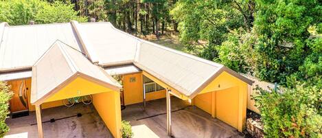 Un edificio amarillo con varias construcciones adosadas, rodeado de un bosque denso.