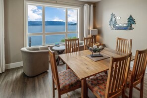 Enjoy meals in this dining area with a wooden table and six chairs, surrounded by a beautiful lake and mountain view.