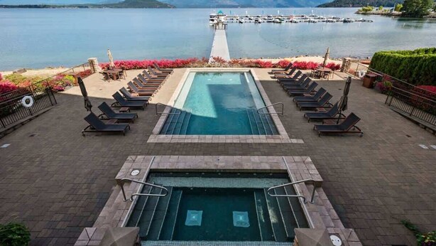 A pool area with lounge chairs and a view of a lake and mountains. - Seasons Lakefront Escape | Pool, Hot Tub & Views (Sandpoint)