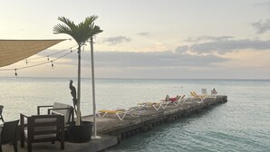 Eine Pier mit Liegestühlen und einem Tisch, mit Blick auf das Meer.