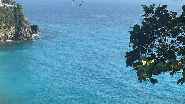 Ein Küstenstrand mit klarem türkisblauem Wasser und einer steilen Klippe.