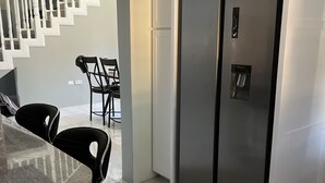 Eine moderne Küche mit einem Edelstahlkühlschrank, einer Marmorarbeitsplatte und einer Treppe, die in eine andere Ebene führt.