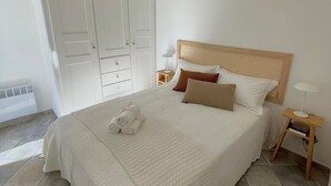 Un dormitorio ordenado con una cama grande, una mesita de noche con lámpara y un armario.