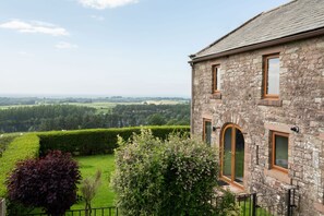 A stone building with a view of a green landscape and a lake.