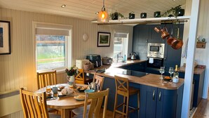 A modern kitchen with wooden cabinetry, a central island, and a hanging copper pot rack. - Green Vale Lodge, Yanwath, dog friendly with hot tub, close to Lake Ullswater (Yanwath)
