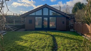 A modern house with a sloped roof, large windows, and a well-maintained lawn. - Green Vale Lodge, Yanwath, dog friendly with hot tub, close to Lake Ullswater (Yanwath)