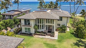 A two-story house with a bay window, solar panels, and a well-maintained lawn. - Hula House - Beachfront North Shore - NEW SPECIAL FALL RATES. (Wailua)