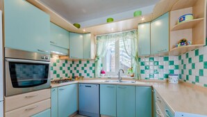 Una cocina con gabinetes azul verdosos, un horno de acero inoxidable y un lavavajillas.