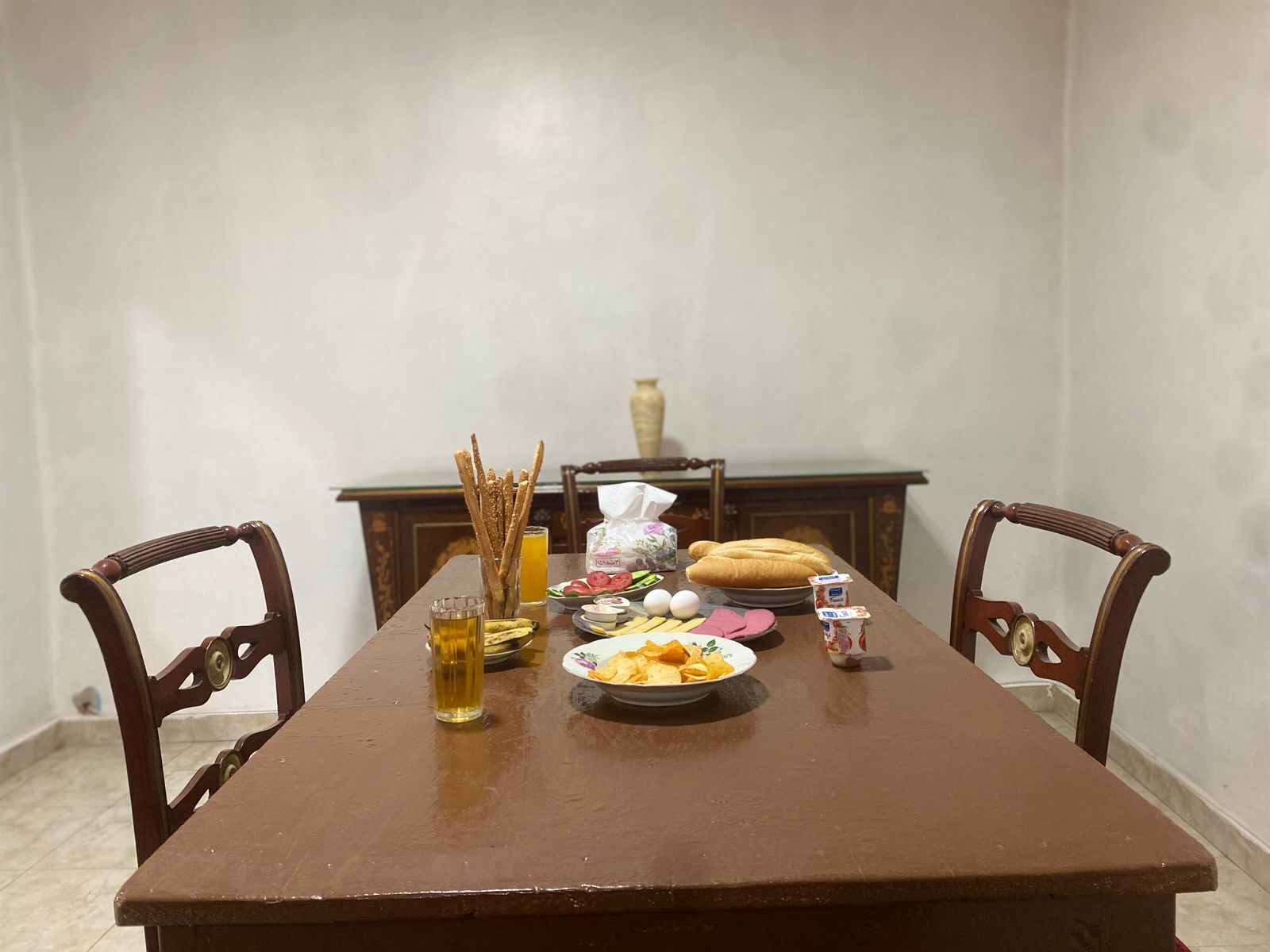 Een eettafel met borden eten, een glas bier en een vaas op de achtergrond.