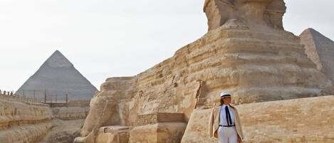 A person standing in front of the Great Sphinx and the Pyramid of Khafra in Giza, Egypt.
