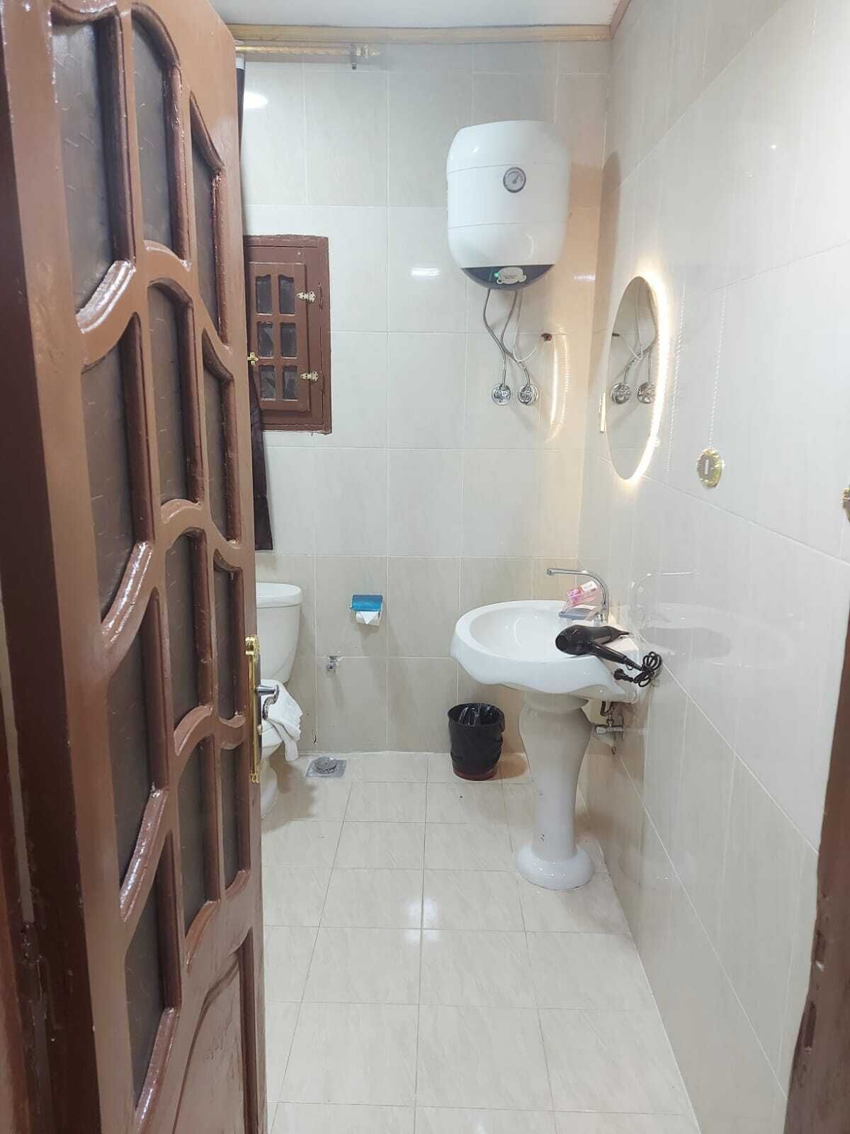 Une petite salle de bain avec des toilettes, un lavabo et un mur recouvert de carreaux blancs.