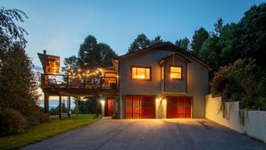 Een twee verdiepingen tellend huis met een garage, een balkon en een goed verlichte oprit.