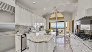 A spacious kitchen with granite countertops, white cabinetry, and a large island. - Stunning Santa Barbara Estate (Santa Barbara)