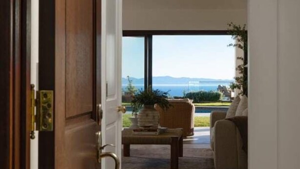 A room with a wooden door, a view of a pool and outdoor furniture, and a clear sky. - Stunning Santa Barbara Estate (Santa Barbara)