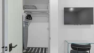 Een moderne badkamer met een handdoekhouder, een douchegedeelte, een stoel met glazen wanden en een tv aan de muur.