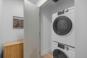A laundry room with a washing machine and dryer, a wooden cabinet, and a framed picture on the wall.