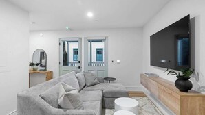 Un salon moderne avec un canapé d’angle, un téléviseur à écran plat et une console en bois.