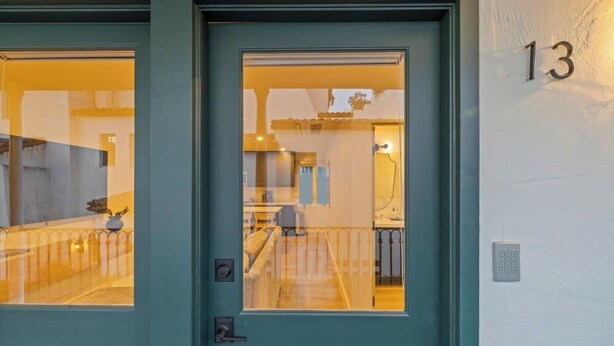 Une porte de couleur turquoise avec un panneau de verre, un système de verrouillage à clavier et le chiffre « 13 » peint sur le mur.
