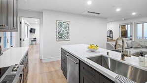 Une cuisine moderne dotée d’un grand îlot central, d’appareils électroménagers en acier inoxydable et d’un design minimaliste.