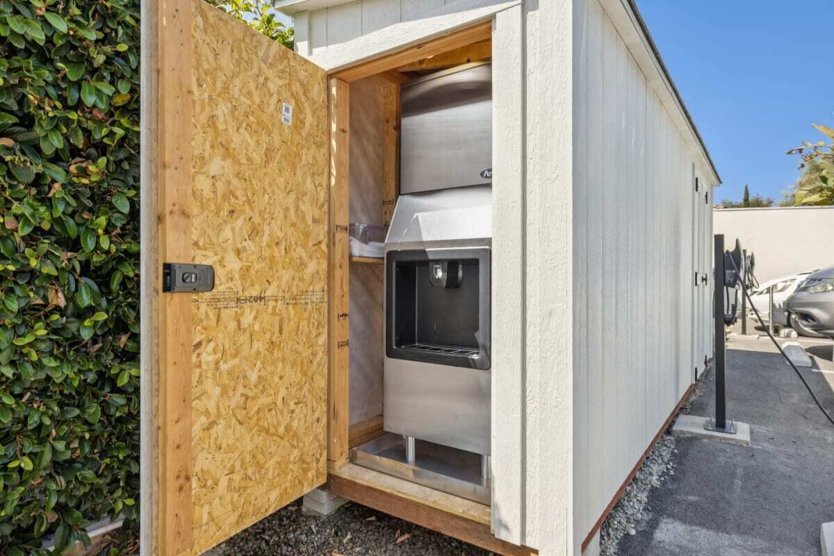 Un bâtiment moderne et compact, doté d’une façade métallique et d’une porte en bois.
