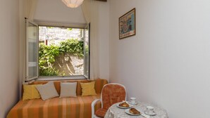 Ein Zimmer mit einem Bett, einem Tisch mit Croissants und einer Tasse, sowie einem Fenster mit Blick auf Grünflächen.