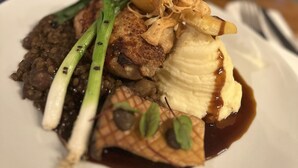 Une assiette remplie de différents plats, accompagnée d’un verre de vin blanc.
