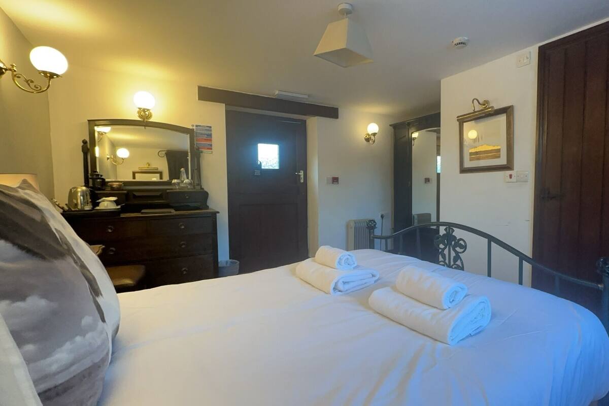 A hotel room with a bed, a dresser, a mirror, and a door.