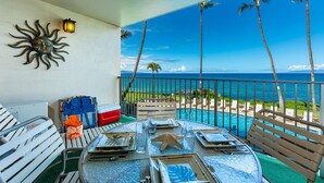 Un balcon avec vue sur l’océan, un élément de décoration sur le thème du soleil et une table dressée pour le dîner.