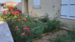 A house with a garden, a wooden trellis, and a stone wall.