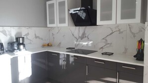 A modern kitchen with dark cabinets, a white countertop, and a black range hood.