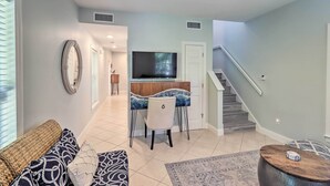 A living room with a sofa, a coffee table, a TV, and a dining area with chairs and a table. - LA CASA ROSADA ~ Perfectly Located 2 BR, 2.5 Ba Home w/ Private Hot Tub! (Key West)