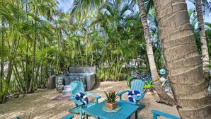 A tropical outdoor seating area with a table and chairs, surrounded by palm trees and a hot tub. - LA CASA ROSADA ~ Perfectly Located 2 BR, 2.5 Ba Home w/ Private Hot Tub! (Key West)