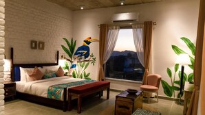 Een slaapkamer met een bed, een bankje, een stoel en een raam met gordijnen.