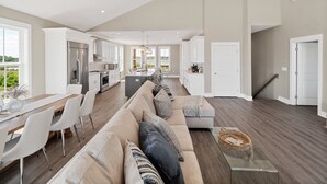 A spacious living area with a large sofa, dining table, and kitchen in the background.