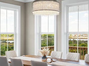 A dining area with a wooden table, white chairs, and a chandelier. - Cabin by the Sea #138 - Private Pool, Second Row Oceanfront & Sound Views! (North Topsail Beach)