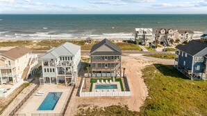 A beachfront property with multiple buildings, a swimming pool, and a view of the ocean.