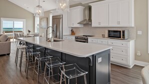 A modern kitchen with a large island, stainless steel appliances, and bar stools.