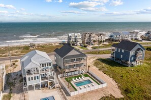 Propiedad frente a la playa con varias casas, una piscina y vista al mar.