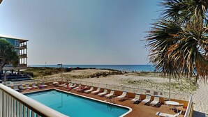 A poolside area with lounge chairs and a view of the beach. - Palm View | Serene Views, Cozy Interior, Near Area Fun! (Gulf Shores)