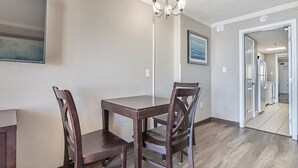 A dining area with a table and chairs, a chandelier, and a hallway leading to other rooms. - Ocean Front 1BR - Caravelle 1036 (Myrtle Beach)