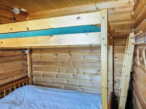 Een houten stapelbed met een blauwe matras, een metalen hoofdbord en een houten trap.