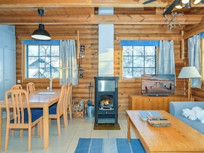 Un intérieur de chalet chaleureux avec une cheminée, des meubles en bois et de grandes fenêtres.