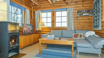 L’intérieur d’un chalet accueillant, avec une cheminée, un canapé, une table basse et un téléviseur.