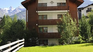 A two-story building with a wooden facade, balconies, and a mountain backdrop.