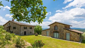 A stone farmhouse with a well-maintained lawn and a clear view of the surrounding countryside.