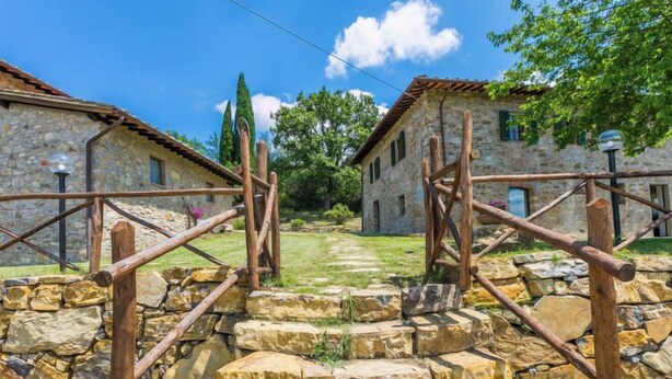 A rustic stone building with a wooden staircase leading up to a stone wall.