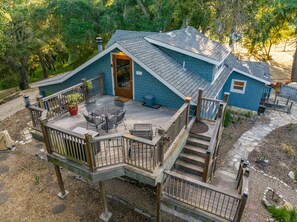 A two-story blue house with a deck, a staircase, and a small garden area.