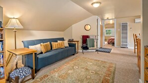 Ein gemütliches Wohnzimmer mit einem blauen Sofa, einem Holztisch, einem gemusterten Teppich und einer Lampe.